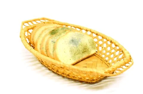 Several slices of bread covered with mold lie in a basket isolated on a white Stock Photos