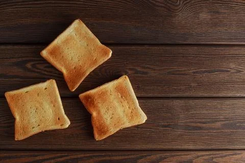 Several slices of toasted bread toasts on a wooden dark background. Stock Photos