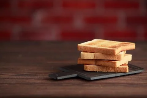 Several slices of toasted bread toasts on a wooden dark background. Stock Photos