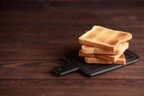 Several slices of toasted bread toasts on a wooden dark background. Stock Photos
