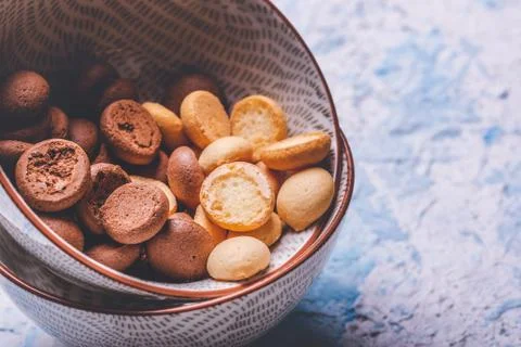 Several sponge biscuits in bowl on light wooden board Stock Photos