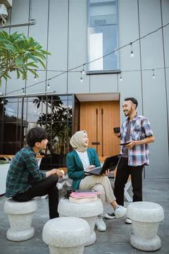 Several students chatting using laptops in front of the building Stock Photos