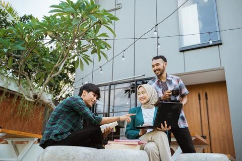 Several students discussing using laptops when meeting in a cafe Stock Photos