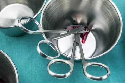 Several suture scissors on a silver tray, traces of blood, conceptual image.. Stock Photos