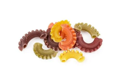 Several uncooked colored creste di gallo pasta on white background Stock Photos