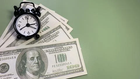 Several US hundred dollar bills with a black alarm clock, Stock Photos