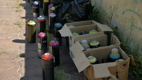 Several used multi-colored spray paint cans stacked near a wall. Stock Footage 299833990