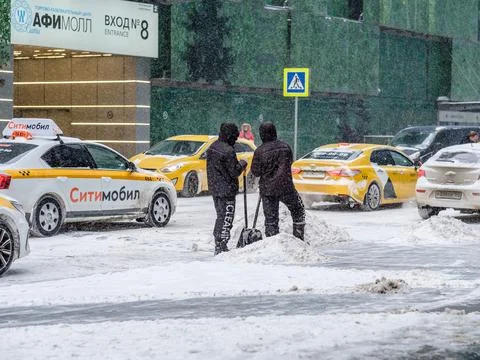 Several utility workers with shovels remove snow from the road during a snowf Stock Photos