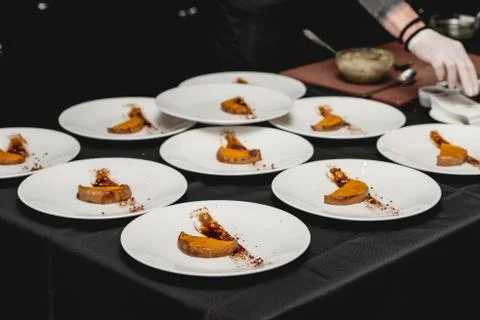 Several white plates on a black table with baked sweet pumpkin and guacamole Stock Photos