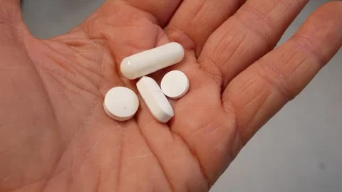 Several white round and oval tablets in an open female hand. Stock Footage 317849655