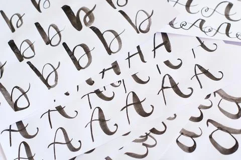 Several white sheets with calligraphic exercises. Calligraphy practice. Stock Photos