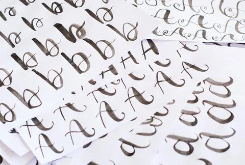 Several white sheets with calligraphic exercises. Calligraphy practice. Stock Photos