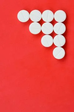Several white tablets lie on a bright red background in the form of a triangu Foto stock