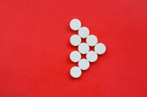 Several white tablets lie on a bright red background in the form of a triangu Foto stock