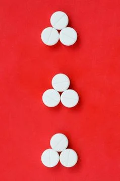 Several white tablets lie on a bright red background in the form of three tri Foto stock