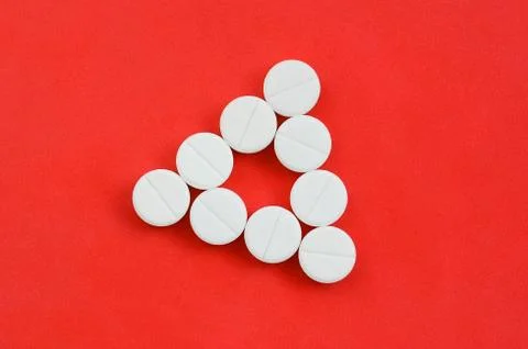 Several white tablets lie on a bright red background in the form of an even t Foto stock