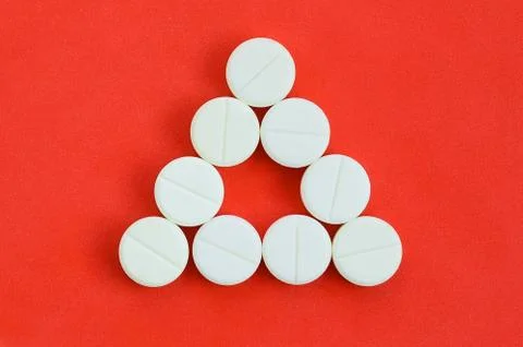 Several white tablets lie on a bright red background in the form of an even t Foto stock