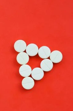 Several white tablets lie on a bright red background in the form of an even t Foto stock
