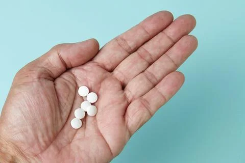 Several white tablets in the palm of a hand 库存照片