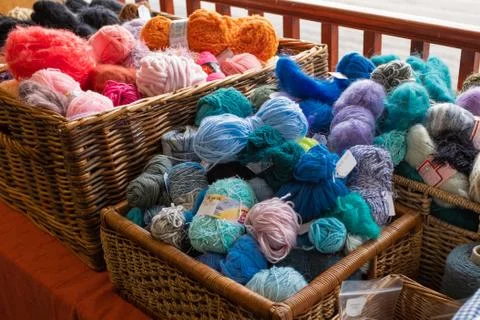 Several  wicker baskets of knitting wool for sale, mostly blues and oranges Stock Photos