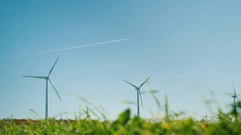 Several wind turbines. In the foreground there is a green grass, in the Stock Footage 83305019