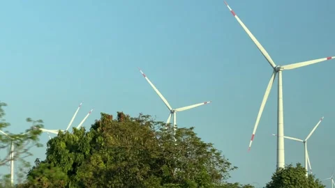 Several wind turbines rotate across an open landscape filmed while driving 動画素材 331205723