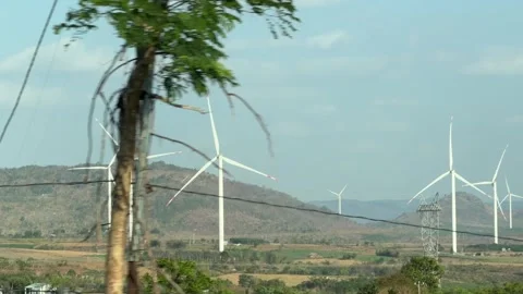 Several wind turbines rotate across open land recorded while traveling through a Stock Footage 340150138