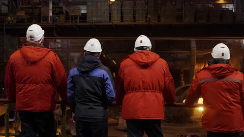 Several workers are standing in the shop of a metallurgical plant. Against the Video stock 177396108
