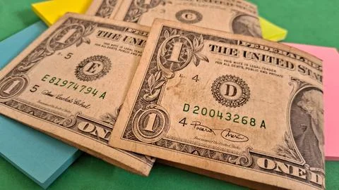 Several worn one dollar bills resting on colorful sticky note pads Stock Photos