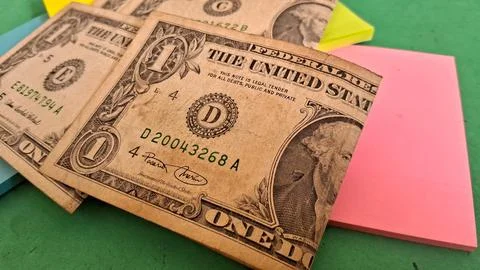 Several worn one dollar bills resting on colorful adhesive note pads Stock Photos