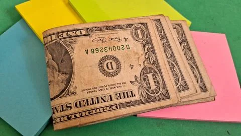 Several worn one dollar bills resting on colorful sticky note pads Stock Photos