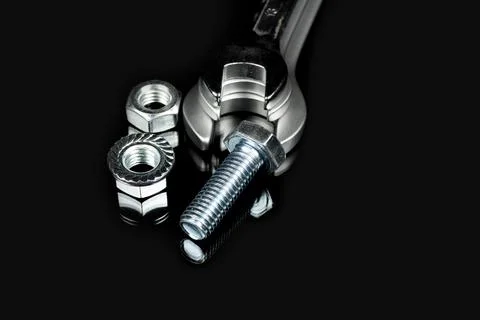 Several wrenches next to nuts and bolts on a black background Foto stock