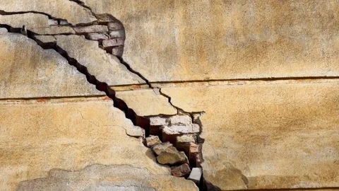 Severe crack in an old plaster wall with exposed brickwork, broken facade Stock Footage 336088949