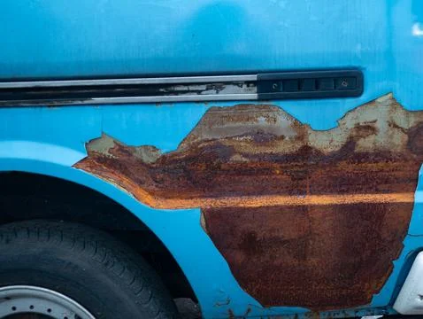 Severe rust corrosion damage on blue car body panel showing oxidation decay.. Fotos Stock