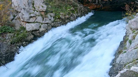 Severe waterfall stream flowing from cave surrounded by rocks Stock Footage 121520604