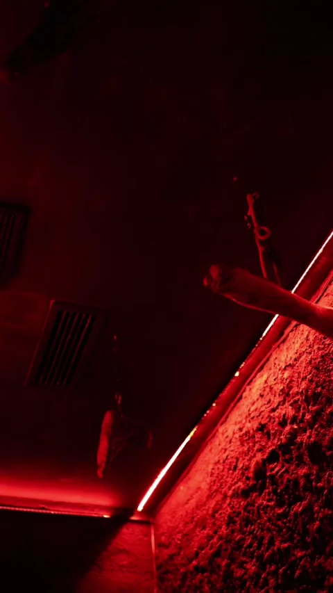 Severed arms hang from chains under intense red Halloween horror lighting 스톡 동영상 345598606
