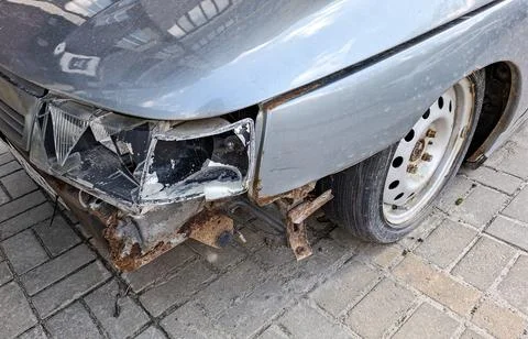 Severely damaged silver car front bumper and broken headlight with rust and.. Fotos de archivo