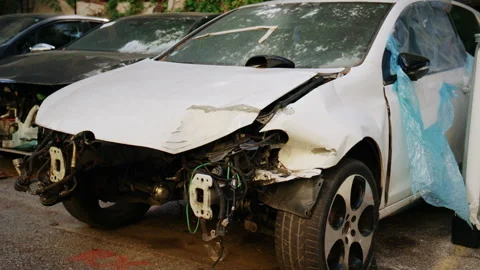 Severely damaged white car with missing front bumper and exposed mechanical Stock Footage 339733129