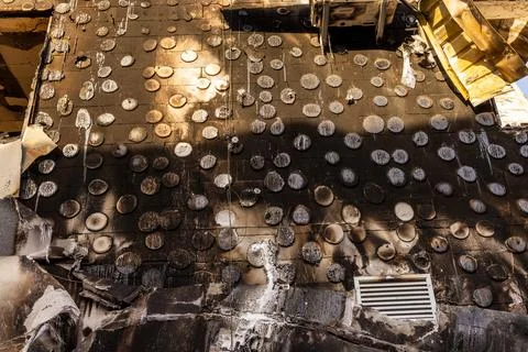 Severely fire damaged building with melted circular tiles, scorched window 스톡 사진