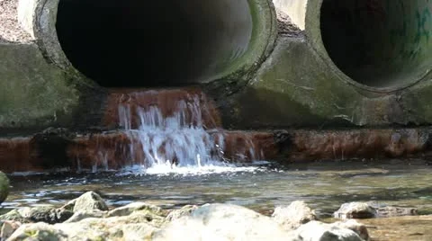 Sewage draining into small stream from a large concrete pipe Stock Footage 10844263