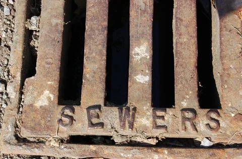 Sewer grating in a roadside gutter Stock Photos