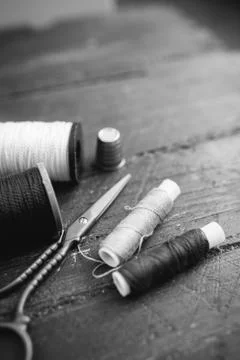 Sewing accessories: bobbins of thread, scissors, needle, thimble on wooden table Foto stock