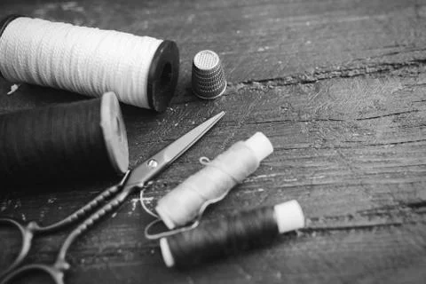 Sewing accessories: bobbins of thread, scissors, needle, thimble on wooden table Stock Photos