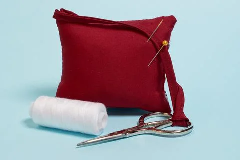 Sewing accessories. A needle pad, scissors and a spool of white thread Stock Photos