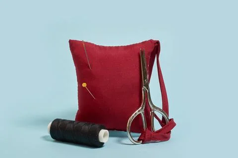 Sewing accessories. A needle pad, scissors and a spool of black thread Stock Photos