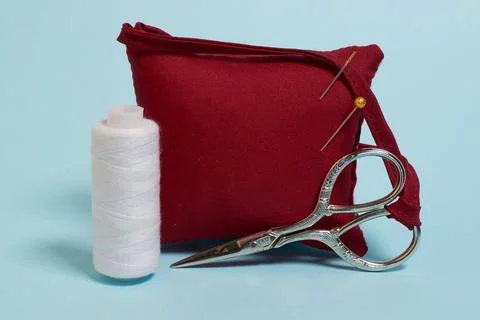 Sewing accessories. A needle pad, scissors and a spool of white thread Stock Photos