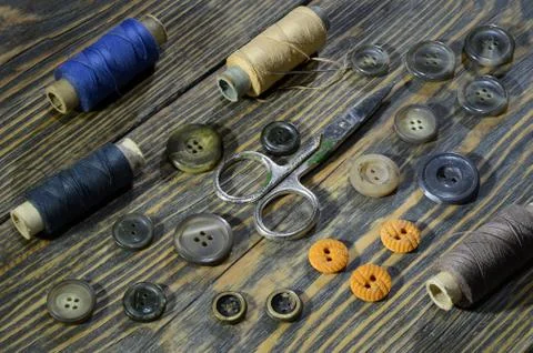 Sewing accessories: scissors, buttons, spools of threads on old wooden table Stock Photos