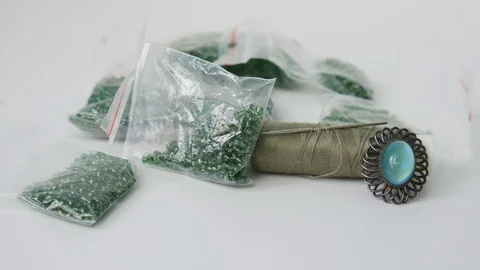 Sewing Accessories. Spool of Thread with a Needle, Brooch and Green Beads Stock Footage 123073653