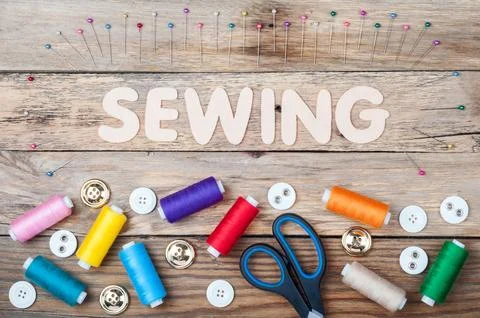 Sewing background with copy space. Colorful threads bobbins, word Sewing, s.. Stock Photos