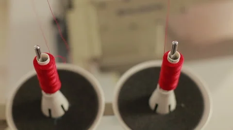 Sewing bobbin being wound up on a sewing machine with red thread. Stock Footage 58051871